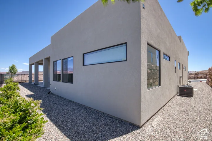 Modern exterior featuring a smooth stucco finish, clean geometric lines, large horizontal windows with dark frames, and a covered patio area