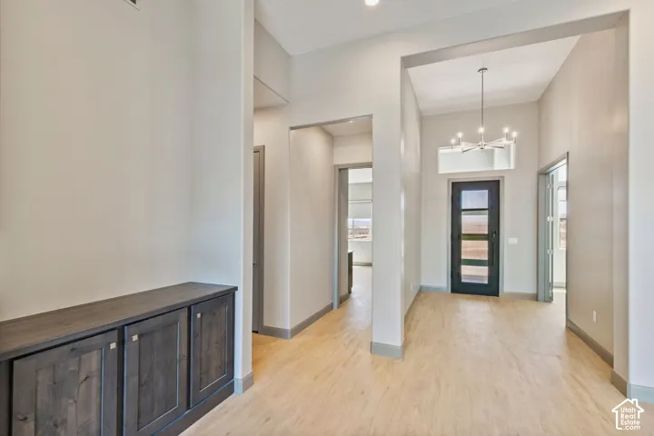 Entryway featuring wood-finish flooring, high ceilings, a multi-light chandelier, a dark-framed glass paneled door, and built-in cabinetry with a dark finish