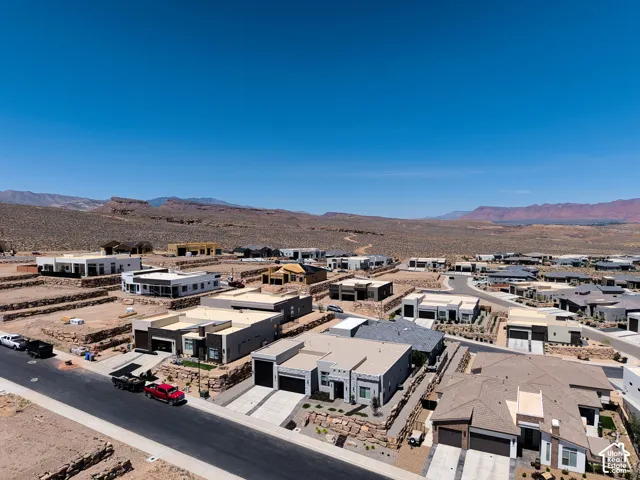 Aerial perspective of a residential development featuring low-profile modern architecture, concrete driveways, structured retaining walls, and surrounding desert landscape