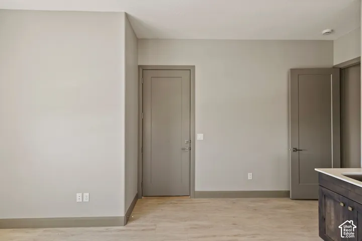 Neutral-toned interior featuring wood-finish flooring, solid-core doors with brushed-metal hardware, and built-in cabinetry with a stone-surface countertop