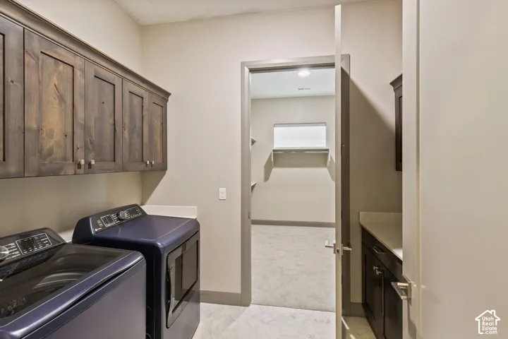 Laundry area featuring stained wood cabinetry, stone-finish countertops, and patterned tile flooring