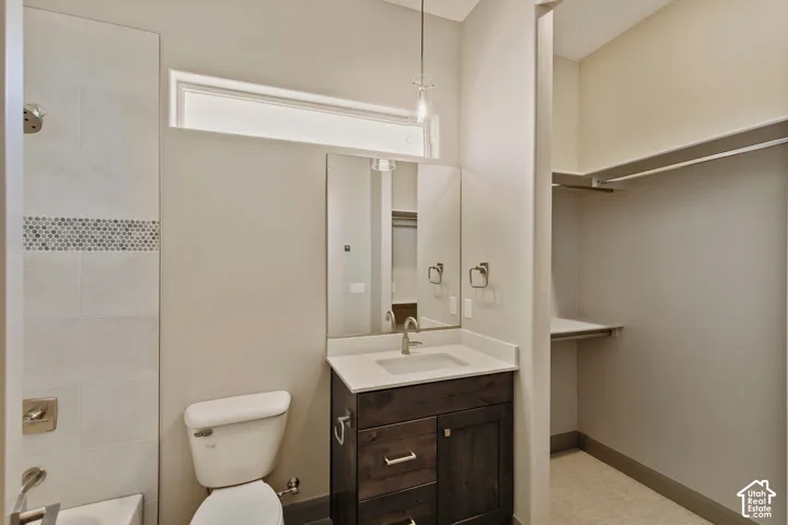 Bathroom featuring a dark wood vanity with a light-toned countertop, rectangular wall mirror, horizontal transom window, and a tile shower surround with decorative mosaic accents