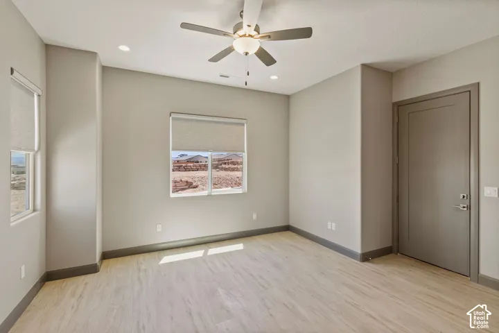 Interior space featuring wood-finish flooring, neutral wall paint, recessed lighting, a ceiling fan with integrated light, and roller shades on the windows