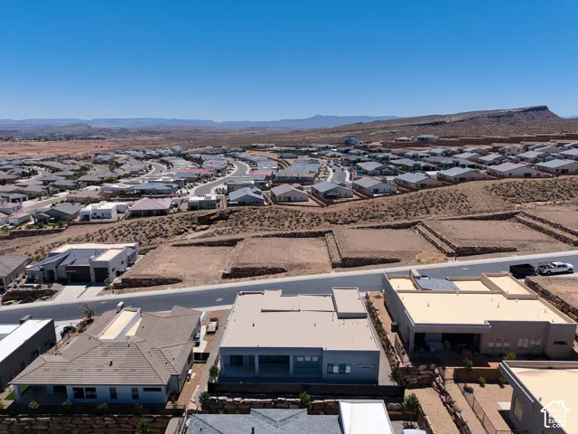 Aerial perspective of a planned community featuring multi-level retaining walls, paved street infrastructure, low-profile residential architecture, and desert mountain topography