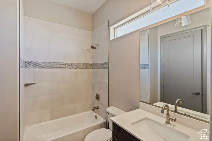 Full bathroom featuring a tub-shower combination with decorative tile inlay, quartz countertop vanity, undermount sink, and clerestory window