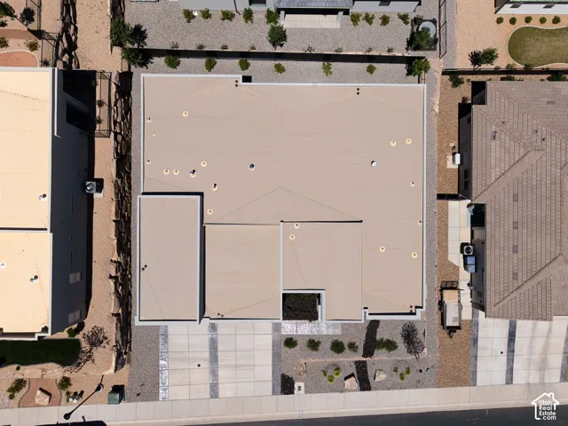 Aerial view of property featuring a flat roofline, concrete driveway, and xeriscaped front grounds