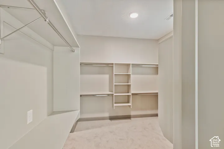 Walk-in closet featuring wall-to-wall carpeting, custom built-in shelving, dual hanging rods, and integrated recessed lighting
