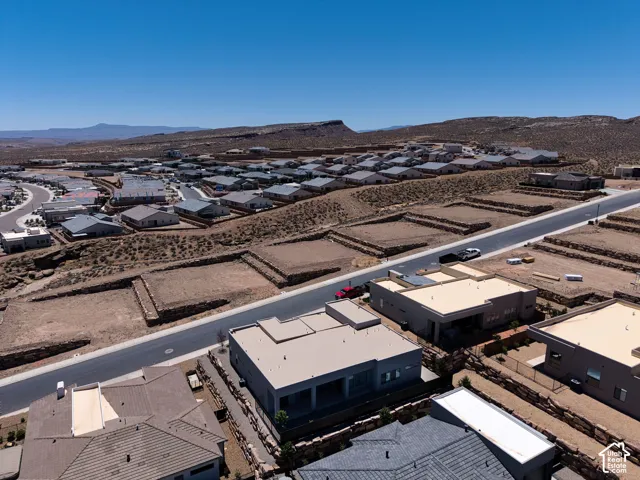 Aerial perspective of a residential development featuring low-profile modern construction, flat roofing systems, stone-retaining walls, and desert landscaping