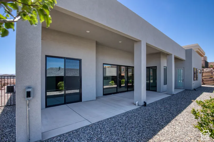 Covered concrete patio featuring recessed lighting, smooth stucco exterior, and multiple sliding glass doors with black framing