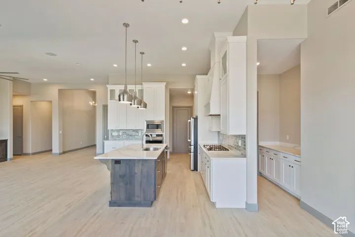 Kitchen featuring white cabinetry, wood-finish flooring, a central island with a contrasting finish, stone-surface countertops, and recessed lighting