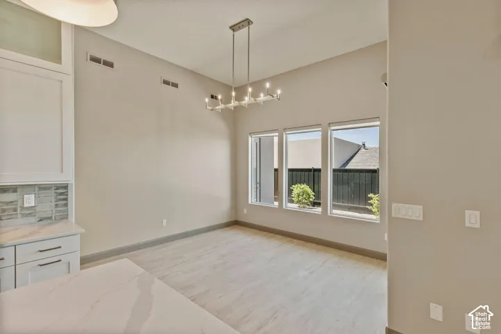 High ceilings, wood-finish tile flooring, custom built-in cabinetry with stone-surface countertop, tile backsplash, and tiered linear chandelier lighting