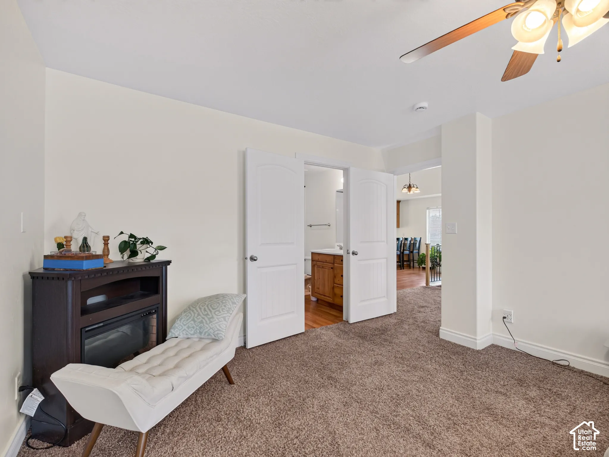 Carpeted interior room featuring a ceiling fan with integrated lighting and double doors