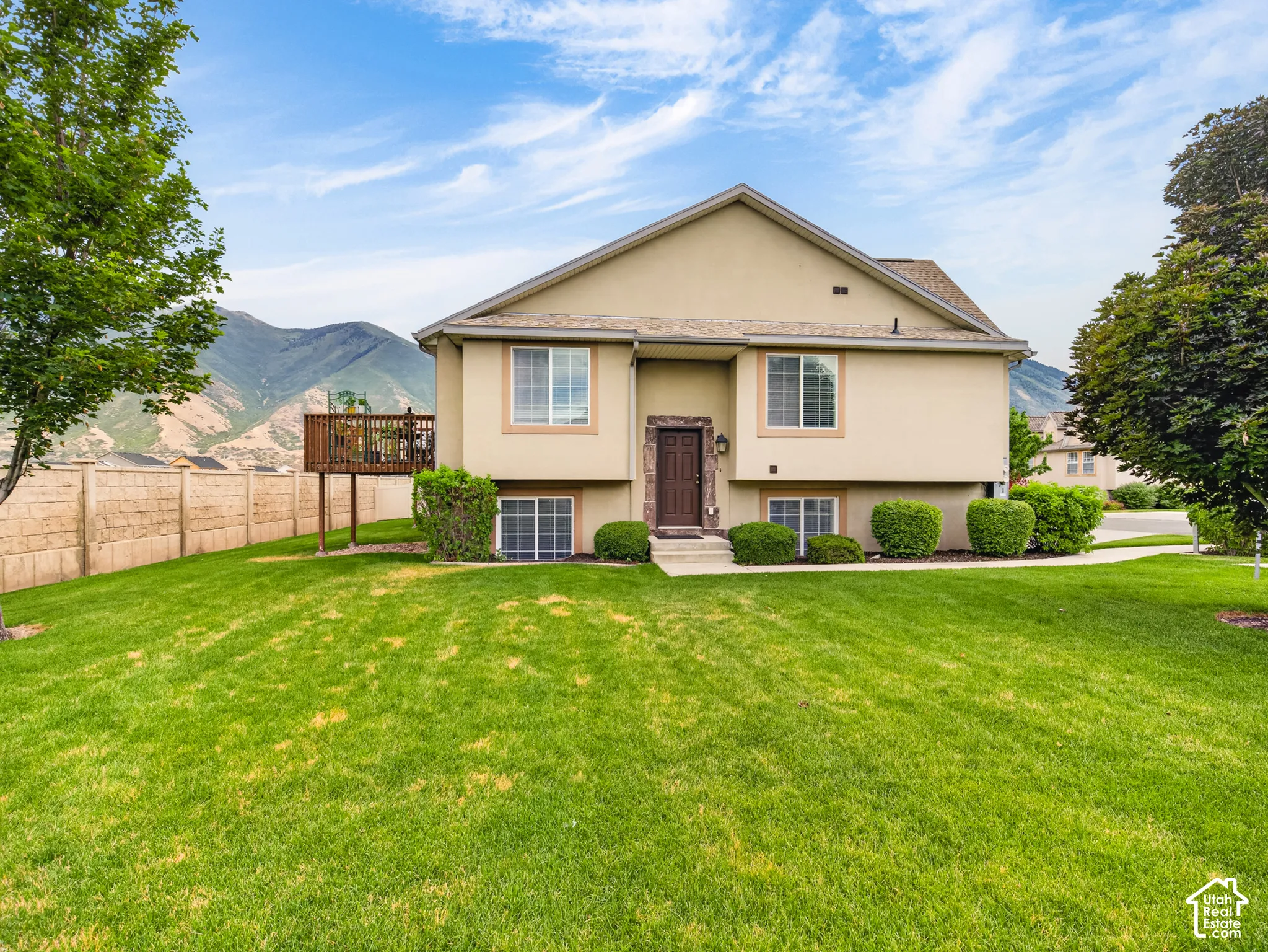 Stucco exterior with elevated wooden deck, multi-pane windows, and mountain backdrop