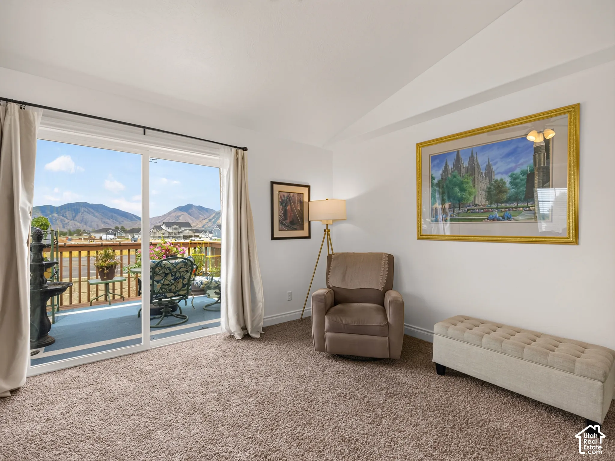 Living area featuring vaulted ceilings, neutral wall-to-wall carpeting, and floor-to-ceiling glass sliding doors opening to an exterior deck with mountain scenery
