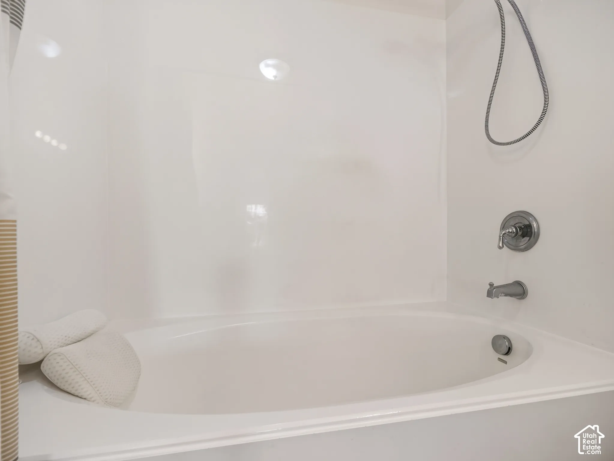 Oval soaking tub featuring a seamless surround, chrome finish faucet, and an adjustable handheld showerhead