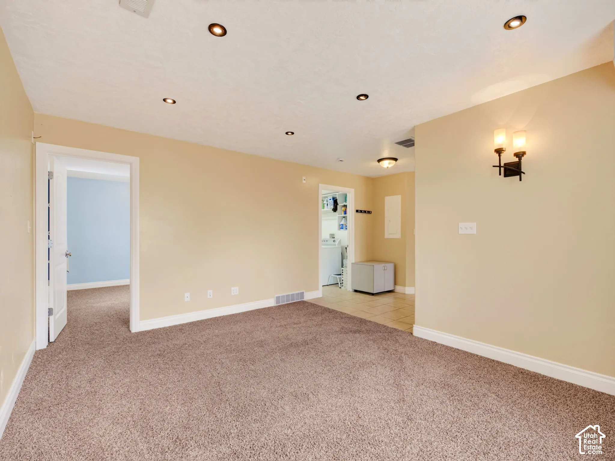 Interior space featuring recessed lighting, wall-mounted sconce fixtures, carpeted flooring, and tiled entryway flooring