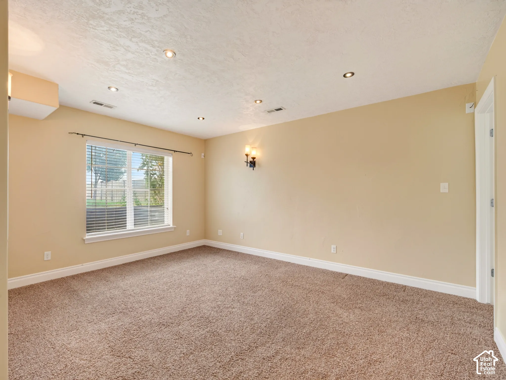 Room featuring wall-to-wall carpeting, recessed ceiling lighting, a wall-mounted light fixture, and a single-pane window with white trim