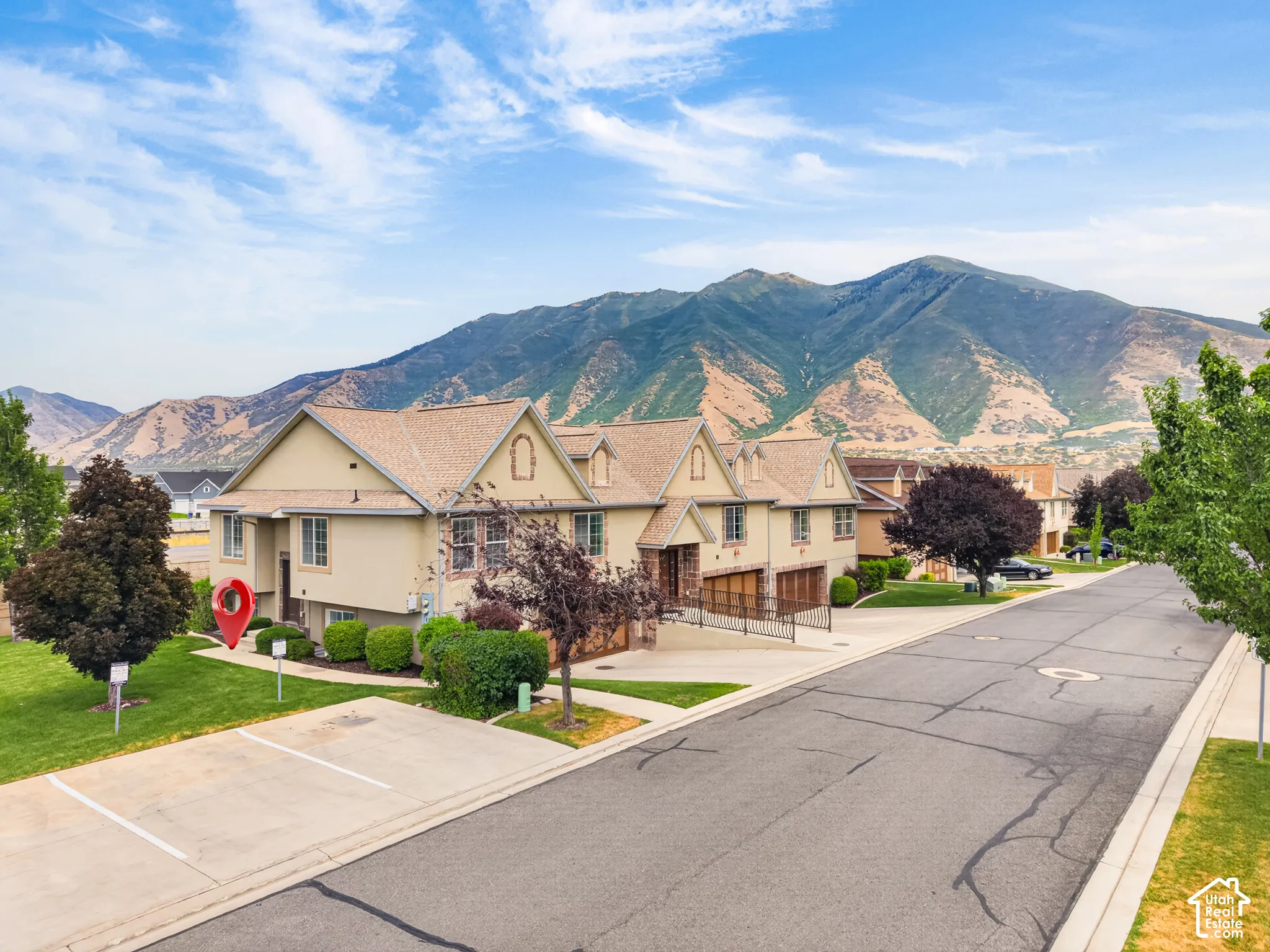 Multi-unit exterior featuring a multi-gabled shingled roof, stucco siding, integrated garage doors, and a mountain backdrop