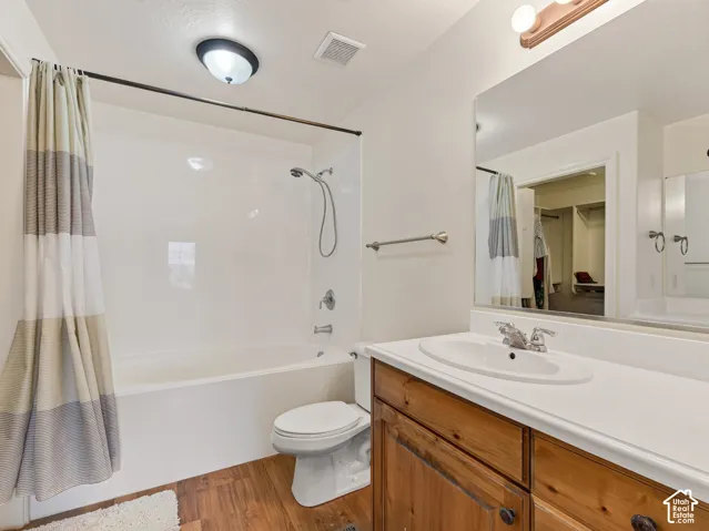 Bathroom featuring wood-finish cabinetry, an integrated sink countertop, a tub and shower combination with a wall-mounted fixture, and a full-width wall mirror