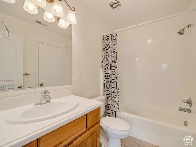Bathroom featuring a wooden vanity, integrated countertop with a molded sink, multi-bulb vanity lighting, and a combination tub and shower enclosure with a wall-mounted fixture