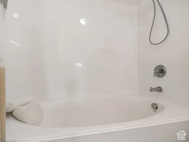 Oval soaking tub featuring a seamless surround, chrome finish faucet, and an adjustable handheld showerhead