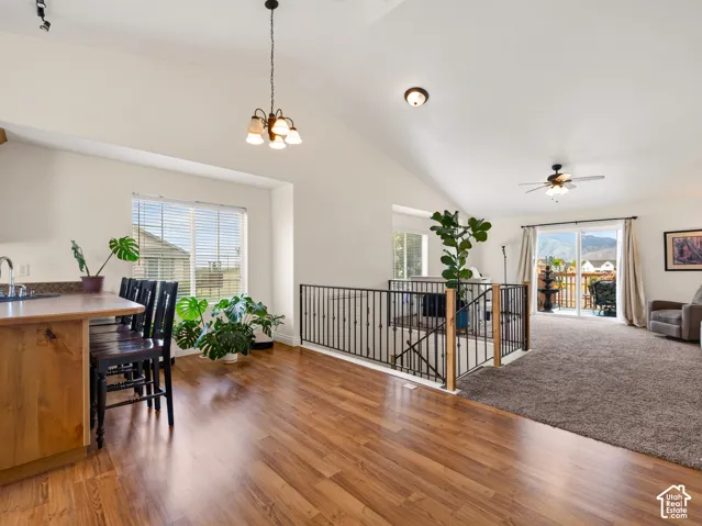Vaulted ceilings, wood-finish flooring, metal staircase railing, and sliding glass doors with mountain backdrop