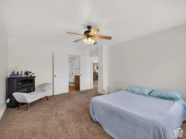Neutral interior featuring wall-to-wall carpeting, a ceiling fan with integrated lighting, and double doors opening to a full bathroom