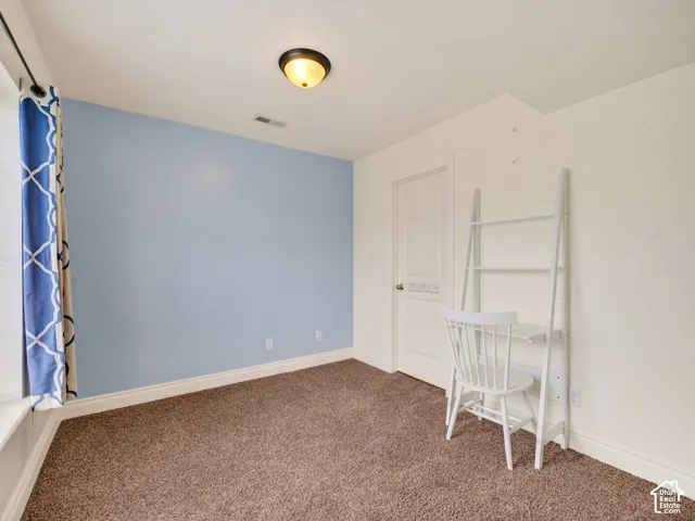 Neutral-toned carpeting, flush-mount ceiling lighting, arched two-panel interior door, and an accent wall