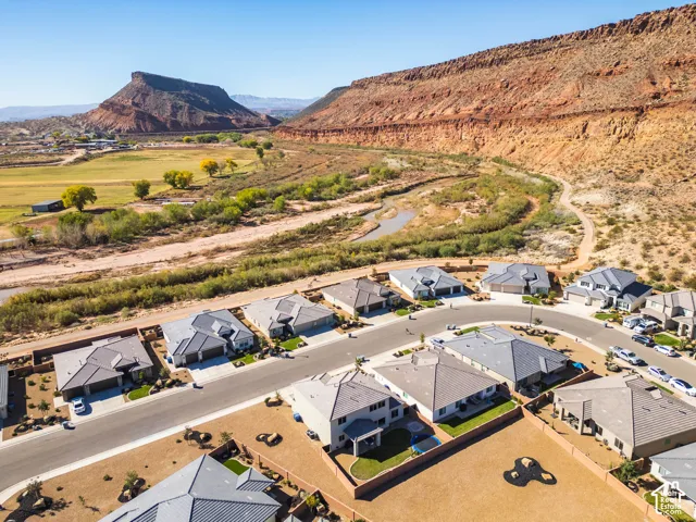 Aerial perspective showcasing a residential community featuring single-story dwellings with pitched roofs, desert-inspired landscaping, and proximity to expansive natural rock formations