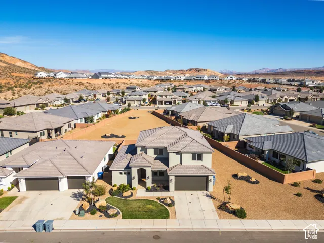 Two-story residence featuring a concrete tile roof, stucco exterior, attached multi-car garage, and desert-style landscaping