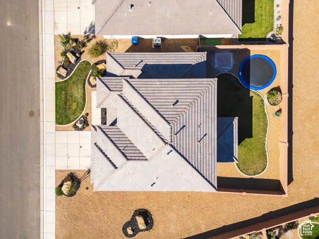Aerial perspective of the property featuring a concrete tile roof, manicured lawn areas, desert landscaping, and walled perimeter