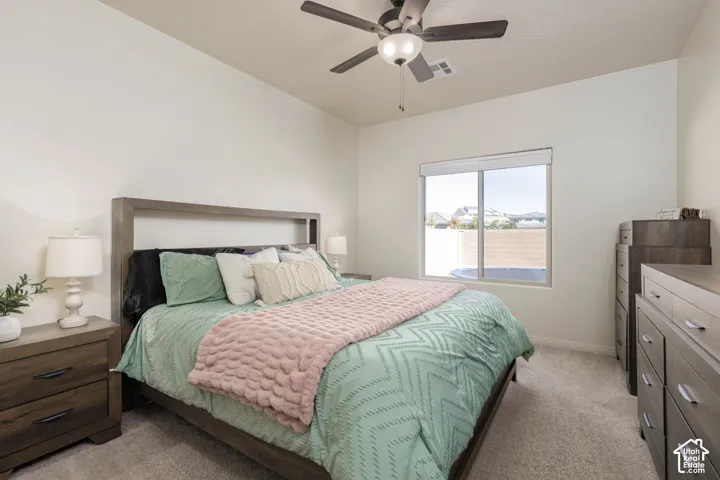Room featuring neutral wall tones, carpeted flooring, a sliding window with white roller shade, and a central ceiling fan with integrated lighting