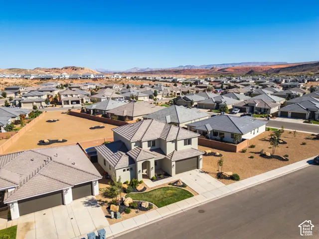 Two-story residence featuring a tile roof, stucco exterior, attached multi-car garage, concrete driveway, and professional landscaping