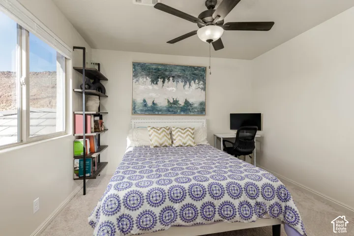 Bedroom featuring carpeted flooring, a ceiling fan with integrated lighting, and a large window
