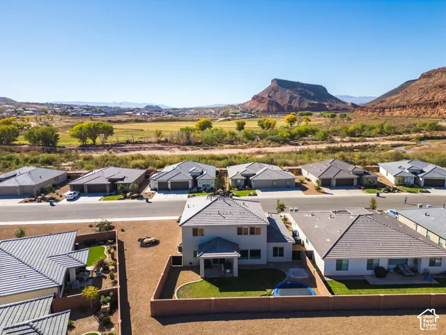 Aerial perspective featuring a two-story residence, a private fenced backyard with a grass lawn, a tiled roof, and a backdrop of expansive mountain scenery