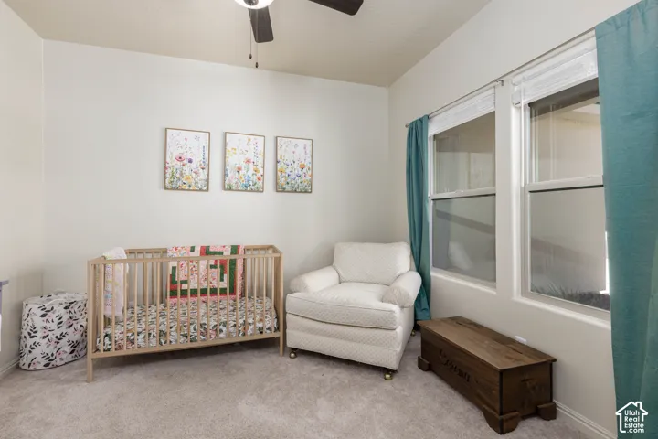 Neutral-toned interior space featuring neutral wall-to-wall carpeting, dual windows with white horizontal blinds, and a ceiling-mounted light fixture with integrated fan