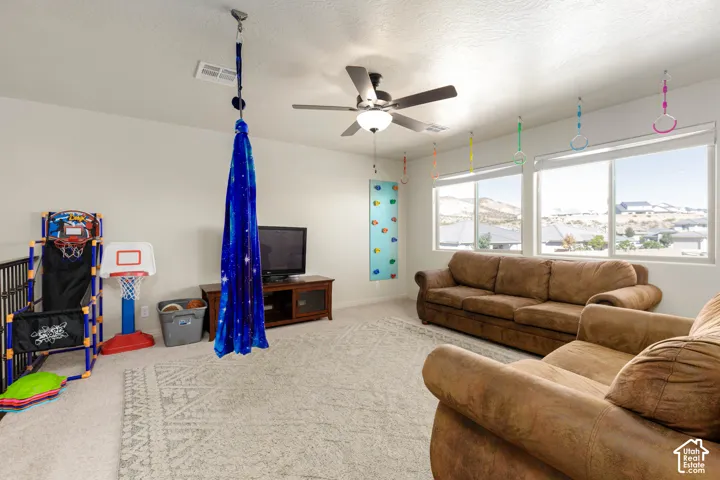 Neutral wall tones, carpeting, and a ceiling fan with integrated lighting