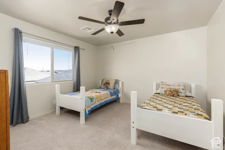 Neutral-toned carpeting, large sliding window with exterior horizon visibility, and a five-blade ceiling fan with integrated lighting