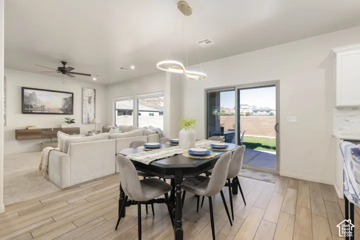 Open-concept space featuring wood-finish tile flooring, a geometric LED pendant light fixture, a ceiling fan, and sliding glass doors