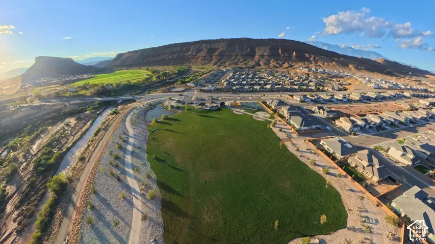 Aerial perspective highlighting expansive green space, paved recreational pathways, proximity to natural rock formations, and desert landscape features