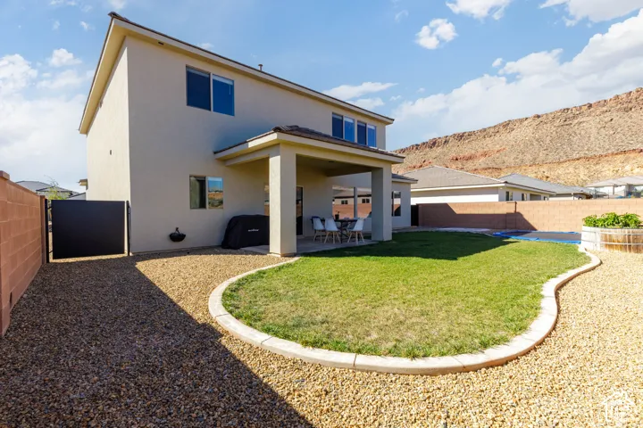 Exterior featuring a covered patio, fenced backyard with a grass lawn, decorative concrete curbing, and a mountain backdrop