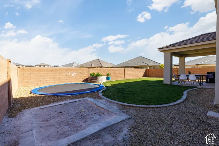 Rear yard featuring a covered patio, manicured lawn, concrete curbing, and perimeter masonry walls