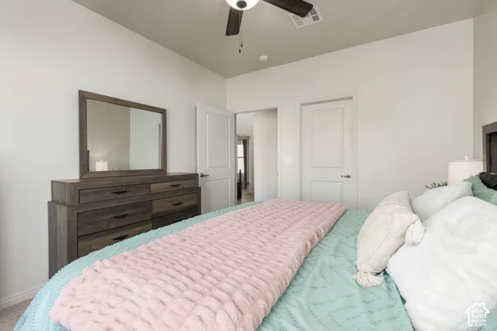 Neutral-toned room featuring a ceiling-mounted fan with integrated light, two interior panel doors, and neutral wall-to-wall carpeting