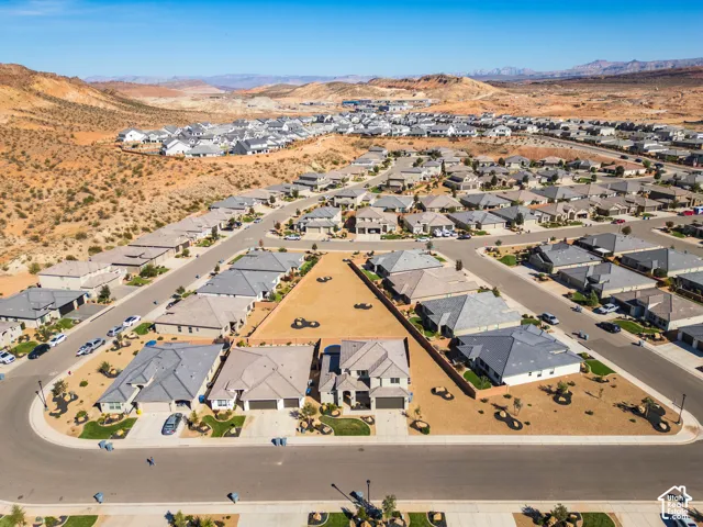 Aerial perspective of a multi-level residence featuring a multi-car garage, pitched roofline, stone and stucco facade, and desert landscaping