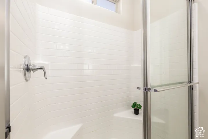 Walk-in shower featuring white subway tile surround, integrated corner seating, polished chrome fixtures, and a glass door enclosure