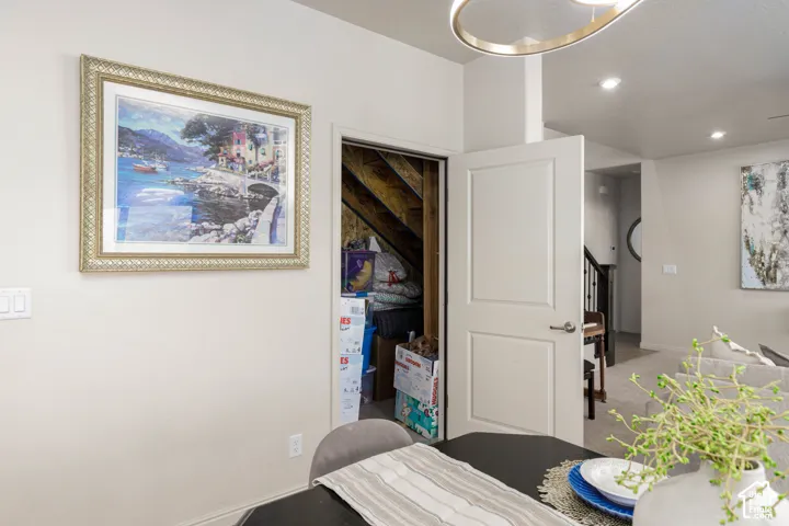 Enclosed under-stair storage area with a paneled interior door, recessed lighting, and a modern circular metal chandelier