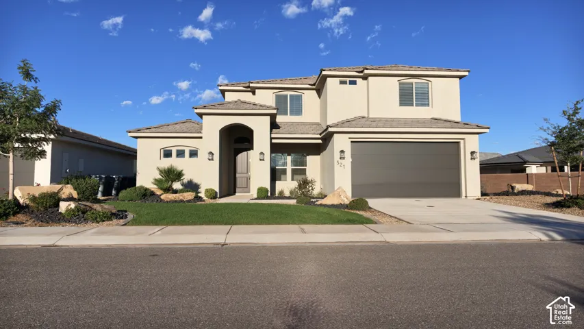 Two-story exterior featuring a stucco facade, arched entryway, tile roof, and a two-car garage