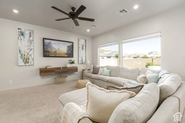 Living area featuring a floating wood-finish media console, recessed lighting, ceiling fan, and large windows with integrated blinds