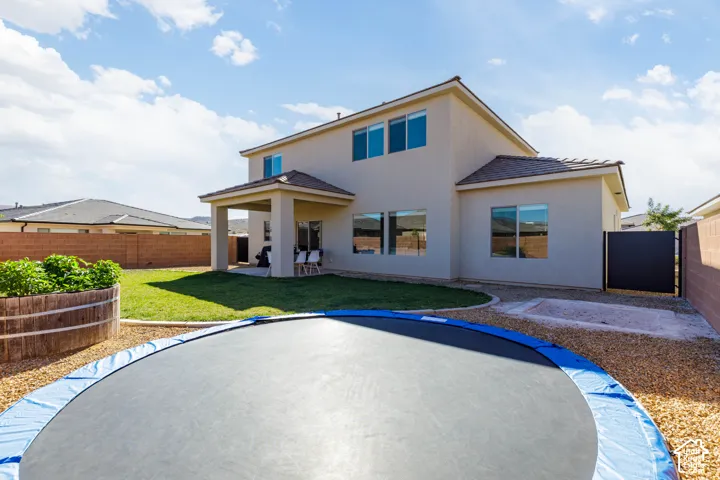 Stucco two-story exterior featuring a covered patio, fenced backyard, low-maintenance gravel landscaping, and a manicured lawn