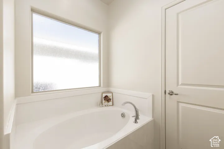Oval soaking tub with a chrome faucet, frosted privacy window, and paneled interior door